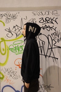 a man standing in front of a wall covered in graffiti